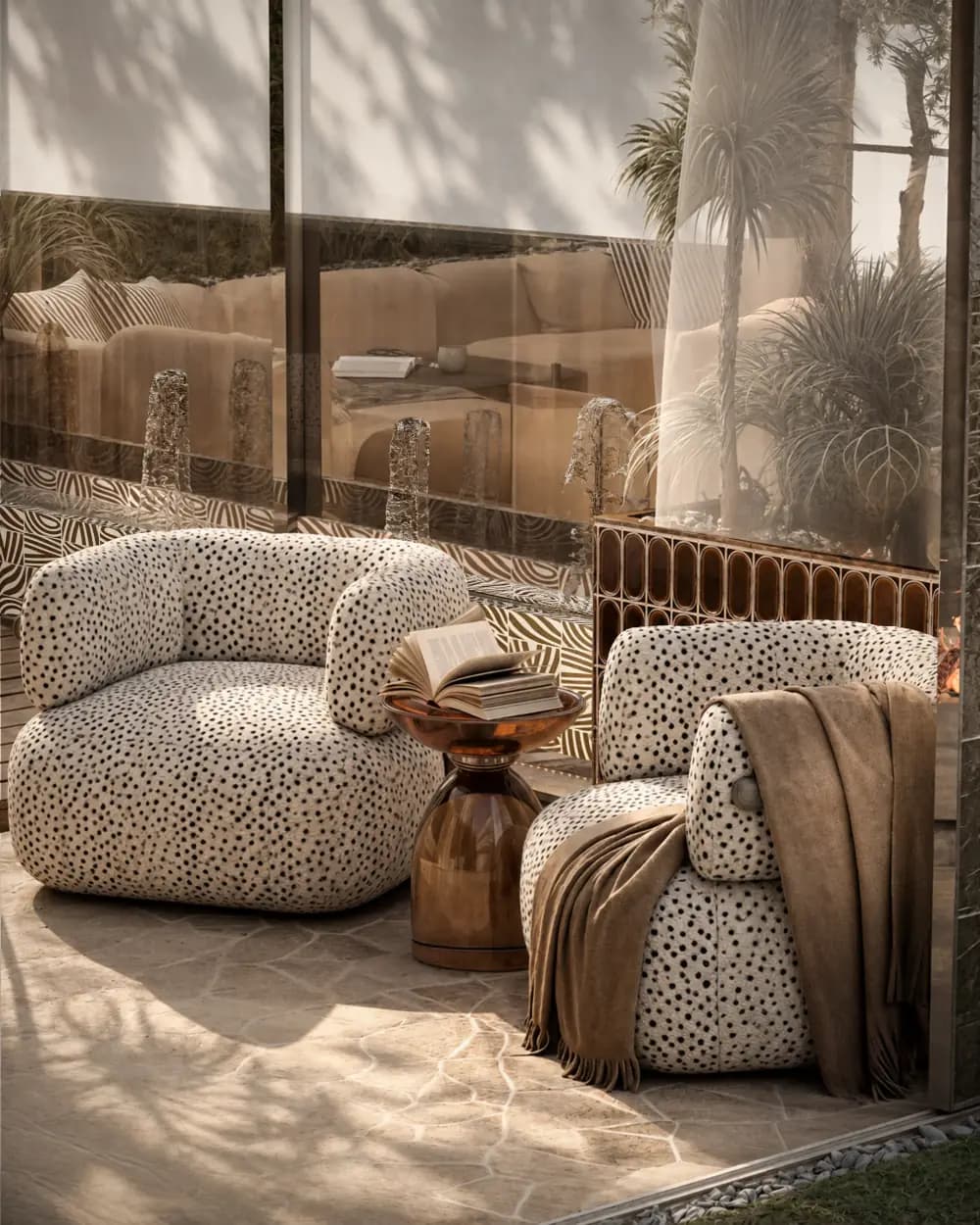 Two spotted bouclé lounge chairs and a copper side table on a stone terrace